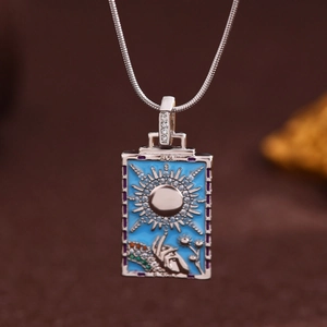 Detail of silver tarot pendant with blue enamel sun design and Roman numeral XIX