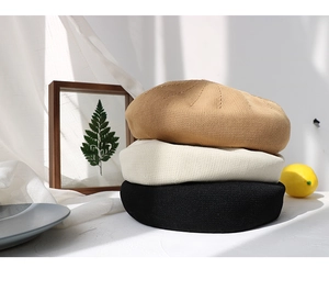 Three knitted berets in khaki, beige, and black colors stacked in a natural light setting