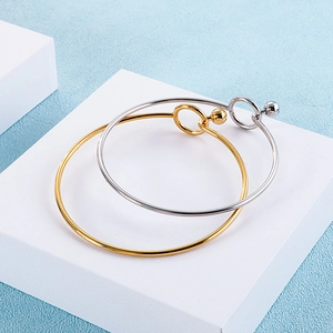 Detailed view of gold and silver minimalist bangles with spherical clasps on display