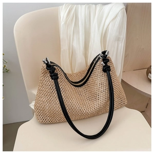 Detail of hand-woven straw tote bag with black strap and metallic zipper closure