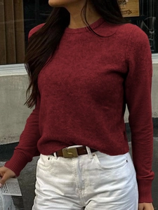 Dettaglio di un maglione da donna in maglia rosso scuro con polsini a coste e girocollo