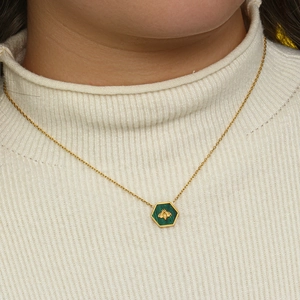 Detailed view of a gold bee pendant necklace with green malachite stone on a sweater