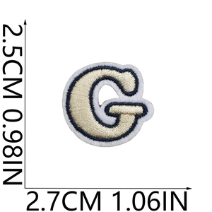 Detail of embroidered letter G patch in cream and navy blue showing precise 2.7cm width