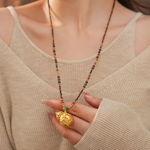 Detailed close-up of a golden hollow gourd pendant with mixed color tiger eye stone beads