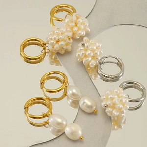 Gros plan de boucles d'oreilles perles et pampilles avec cerceaux dorés et reflets miroir