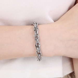 Gros plan d'un bracelet gourmette en acier inoxydable poli argenté au poignet
