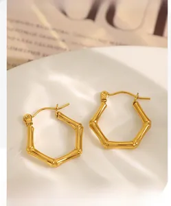 Macro detail of golden hexagonal bamboo texture earrings on a minimalist ceramic plate