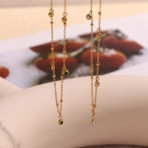 Detail of 18K gold plated necklace featuring green zircon stone and small metal beads