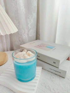 Macro view of ocean-themed soy candle featuring seashells and starfish on cream wax