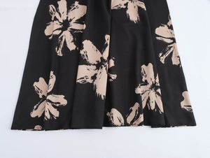 Detail of floral print maxi dress featuring beige flowers on smooth black fabric