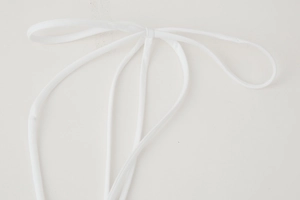 Close-up of a white tied bow detail and fine textile texture on a summer dress
