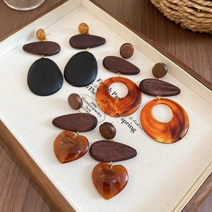 Detail of vintage wooden and amber resin earrings in heart and oval shapes on linen