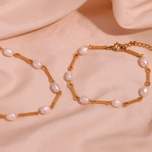 Detail of white irregular pearls and golden spiral metal link connectors on pink satin