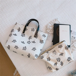Détail du sac cabas en toile crème et pochette avec broderie papillon et anses en cuir brun