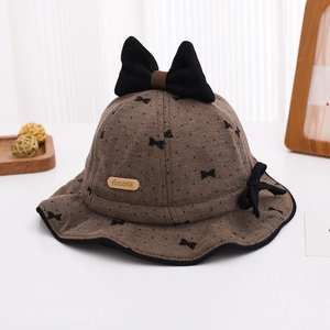 Close-up of brown polka dot baby bucket hat with large bow and leather brand label