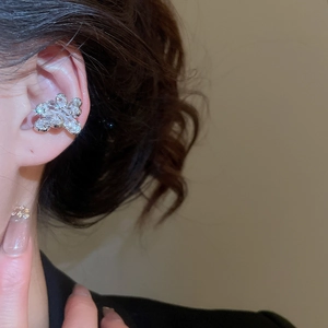 Close-up of elegant silver flower ear cuff with sparkling zircons worn on model ear