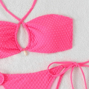 Detail view of pink seersucker bikini with textured fabric and white seashell decor