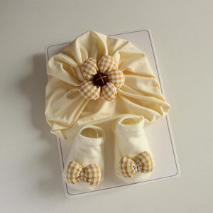Detailed view of yellow infant turban hat with checkered flower and matching bow socks