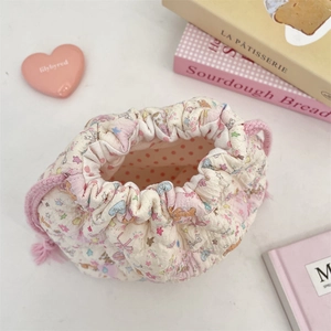Macro detail of quilted cotton makeup bag featuring dual pink tassels and floral patterns