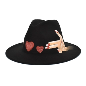 Detail of black wool fedora featuring red glitter hearts and colorful hand-painted art