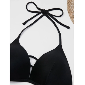 Detailed close-up of a black halter bikini top with cross-straps and textured fabric