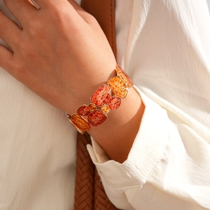 Close-up of golden wide bracelet with amber geometric resin blocks on white fabric