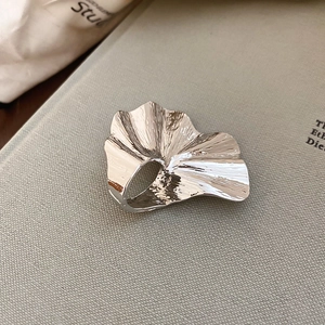 Macro detail of silver ginkgo leaf ring with artistic pleated texture and irregular edges