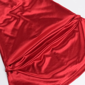 Detailed macro view showing the smooth texture of red satin fabric for the dress