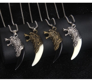 Detail of four stainless steel wolf head necklaces with black and white tusks on display