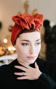 Detailed side view of vintage rust red turban hat with elegant floral fabric folds