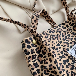 Close-up of leopard print canvas tote bag featuring a metallic snap button and texture
