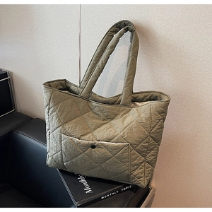 Detail of olive green quilted tote bag featuring a front pocket with black snap button