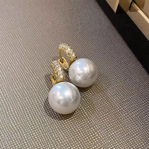 Macro detail of luxury pearl earrings with micro-set zircons on gold-plated bands