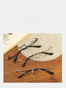 Detailed view of minimalist half-rim metal glasses on a rustic wooden desk with books