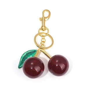 Close-up of glittery dark red cherry keychain with green leaves and gold lobster clasp
