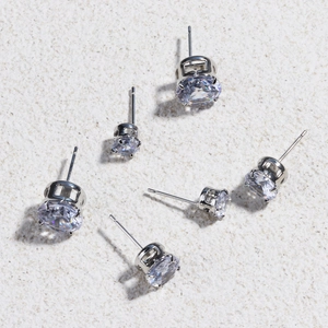 Classic silver copper earrings with round clear zircon on a sandy texture background