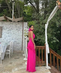 Detail of pink backless halter maxi dress with feather earrings in an outdoor setting