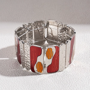 Detail of artistic silver stretch bracelet with red and orange enamel geometric patterns