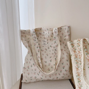 Close-up of creamy white floral canvas tote bag featuring delicate red flower patterns