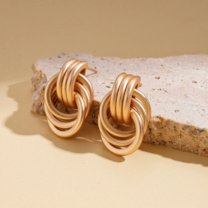 Chic multi-layered geometric knot earrings in gold finish on natural stone background