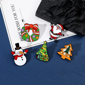 Detail of five Christmas enamel pins with Santa and snowman on a blue background