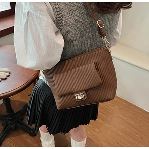 Detail of brown crossbody bag featuring vertical quilted texture and gold metal twist lock