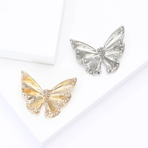Elegant gold and silver butterfly brooches with sparkling rhinestones on white stands