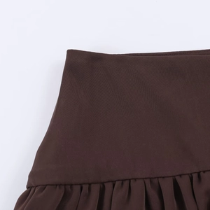 Detail of high-waisted dark brown mini skirt showing fabric texture and gathered waist
