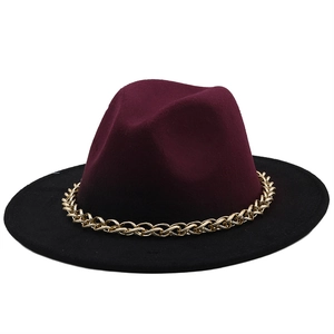 Detail of burgundy and black fedora hat with a bold gold metal chain decoration