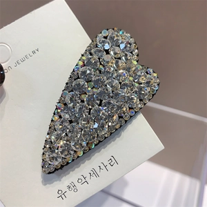 Macro shot of silver heart-shaped hair clip with sparkling crystals on white card