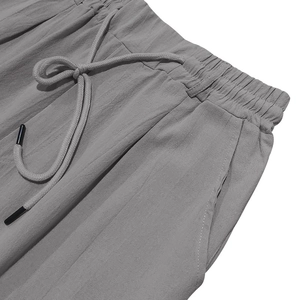 Detailed macro view of the drawstring elastic waistband on light grey linen trousers