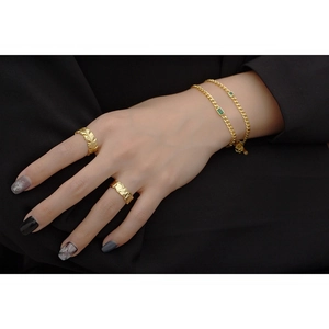 Detailed view of hammered gold ring and layered chain bracelet with green gemstone