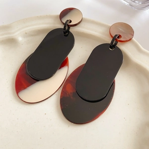 Close-up of vintage tortoiseshell and cream geometric resin drop earrings on ceramic tray