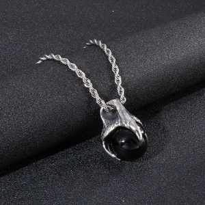Detailed macro view of punk style silver dragon claw pendant holding a black bead stone